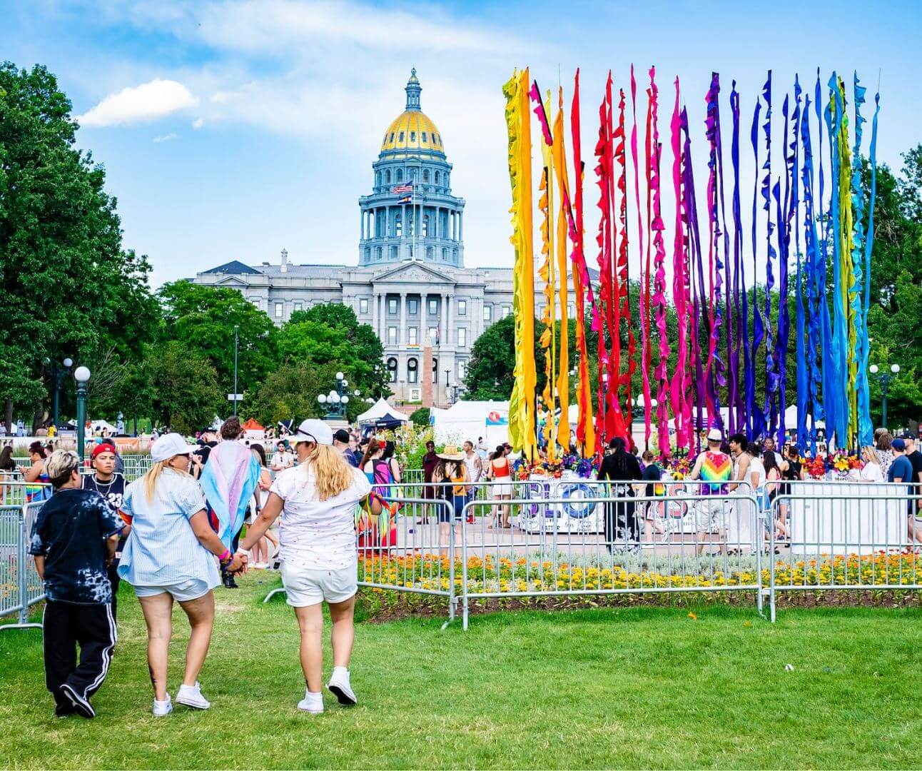Denver PrideFest attendees walk past the rainbow flag art installation towards the Colorado State Capitol