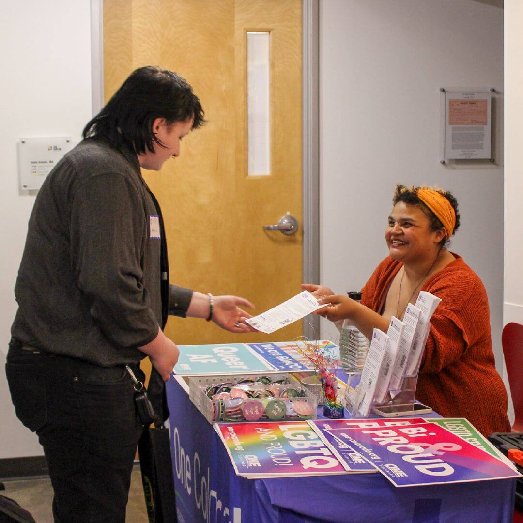 A Rainbow Alley member accepts a resource from an LGBTQ+ organization tabling at an event