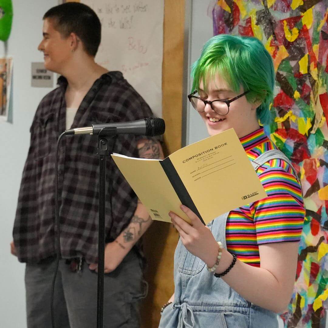 A Rainbow Alley member reads a poem from a journal during Summer Academy