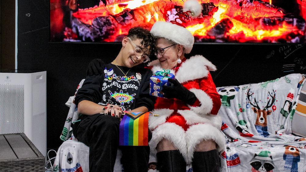 A participant of Rainbow Alley's 2024 Holigay sharing a special moment with Queer Santa