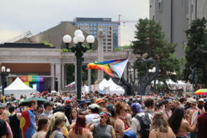 A pride flag waves above the sea of community members attending Denver PrideFest